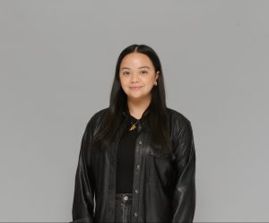 Emily Woo headshot with a black jacket and a grey background